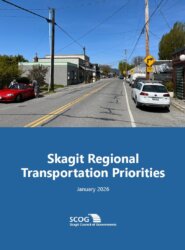 Picture of the front cover of the 22026 Skagit Regional Transportation Priorities. Upper half is a picture of a street lined wwith parked cars in downtown Edison. lower half is a blue background with the document title, adoption date and a white SCOG logo.